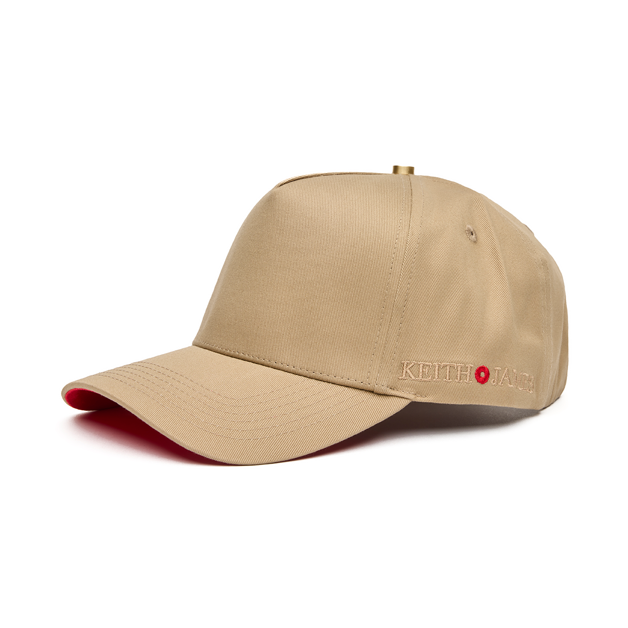 A beige 5 panel baseball cap with an adjustable band and a logo embroidered on the front, featuring a red bottom brim.