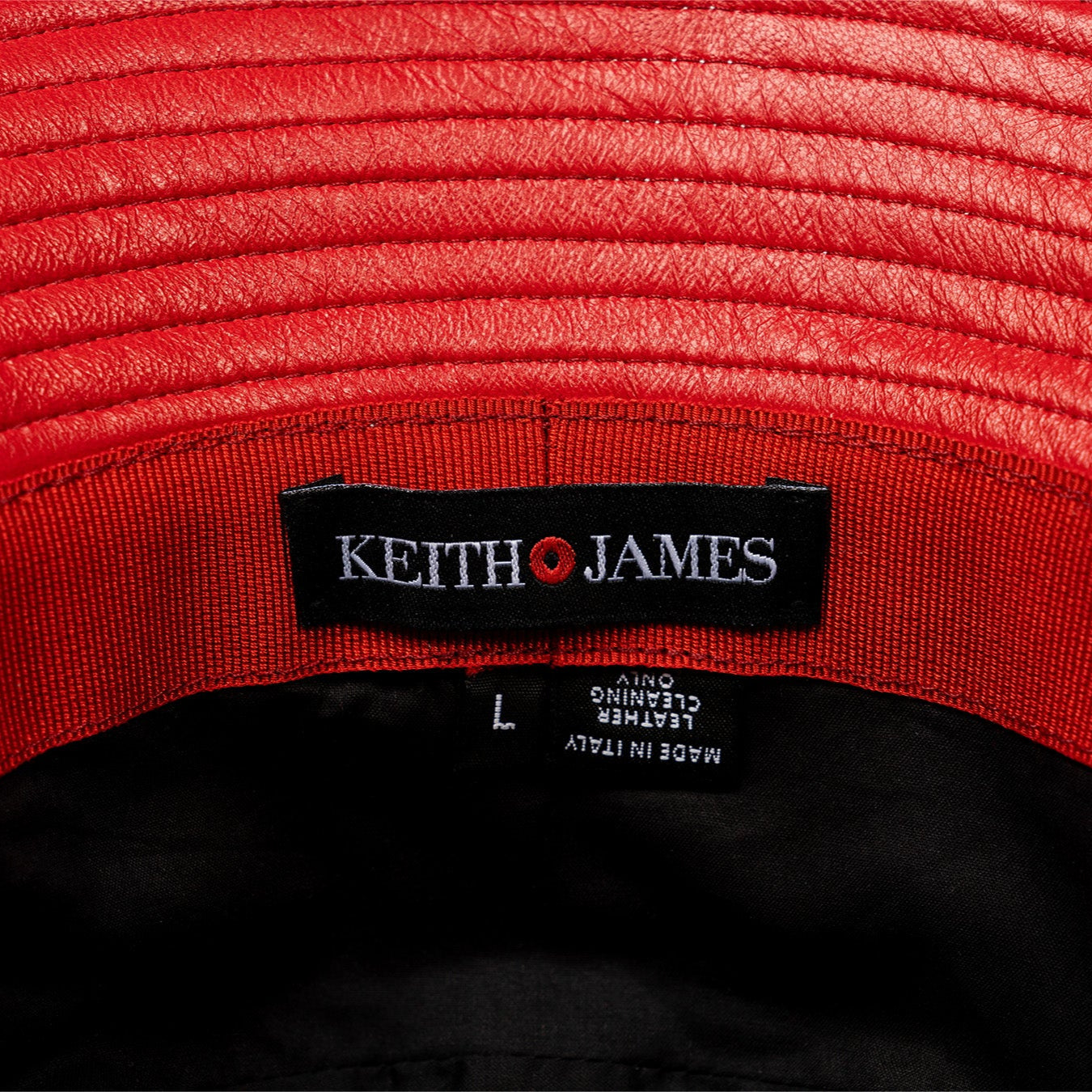A leather bucket hat with a red stamped leather logo circle in the center.