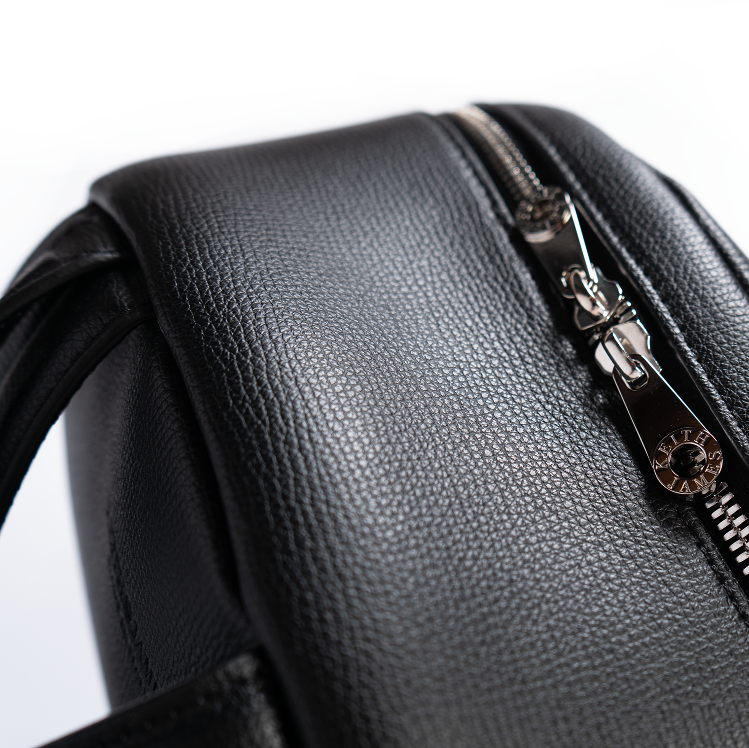 A jet black leather backpack with gold-tone hardware, featuring multiple compartments and a front zipper pocket.