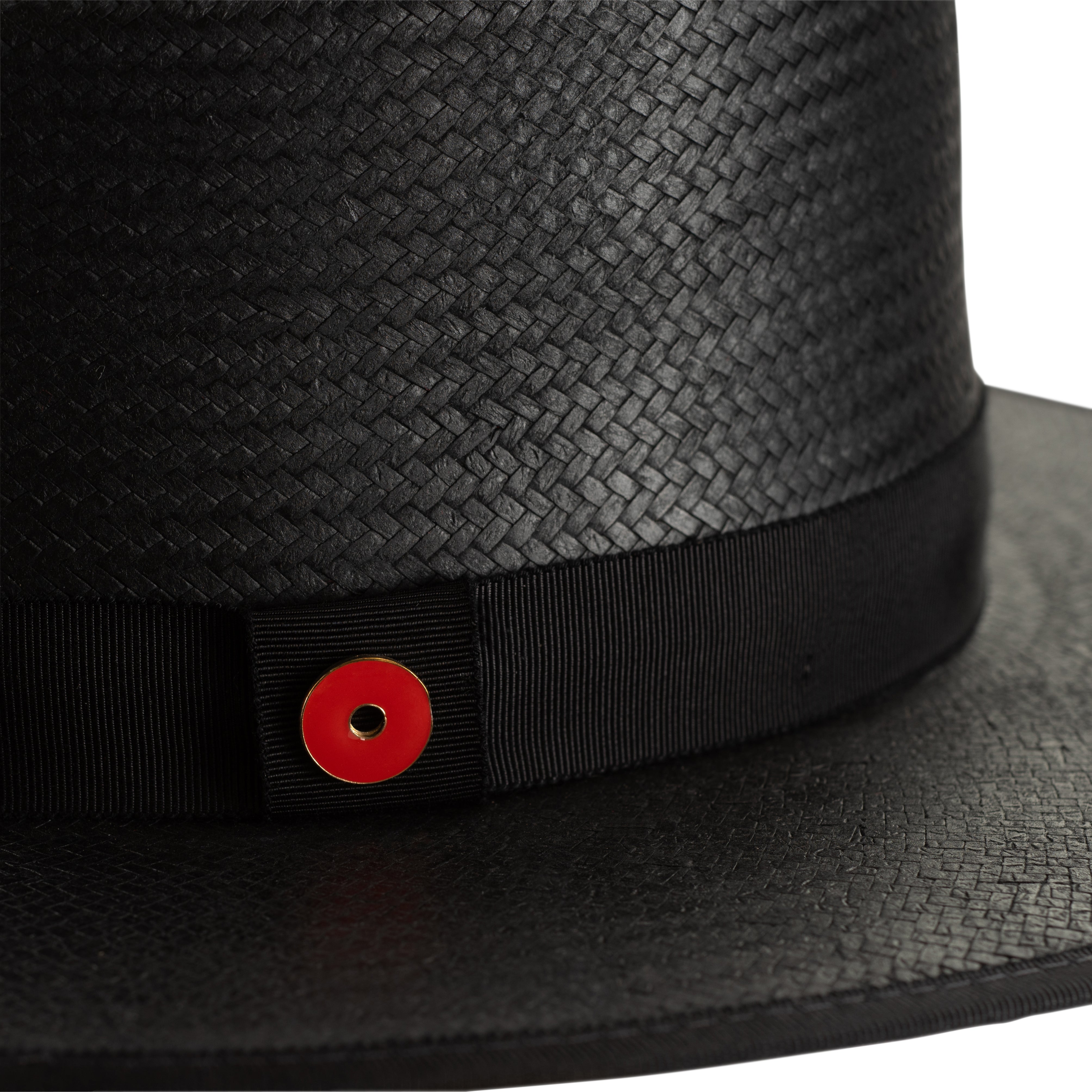 Black straw hat with a red button on a white background