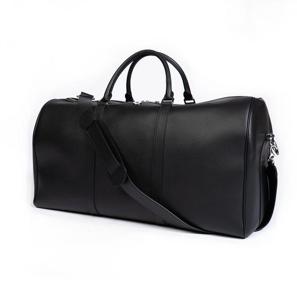 A jet black duffel bag with a detachable strap and gold-tone hardware on a white background.