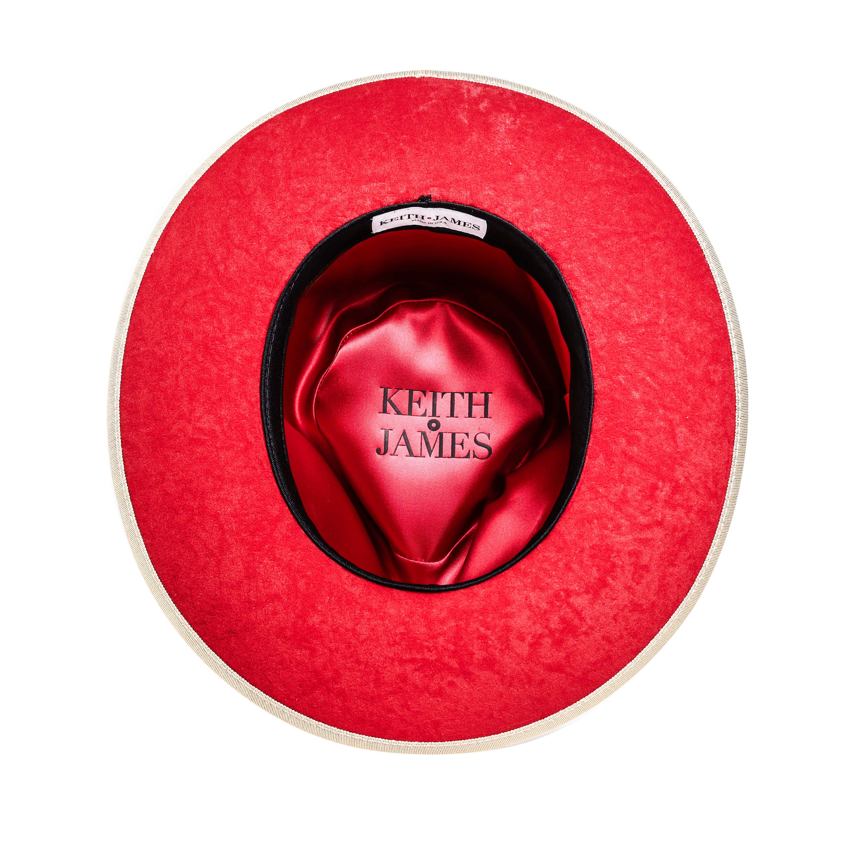 A golden honey colored fedora hat with a wide brim and a signature logo pin on the band.