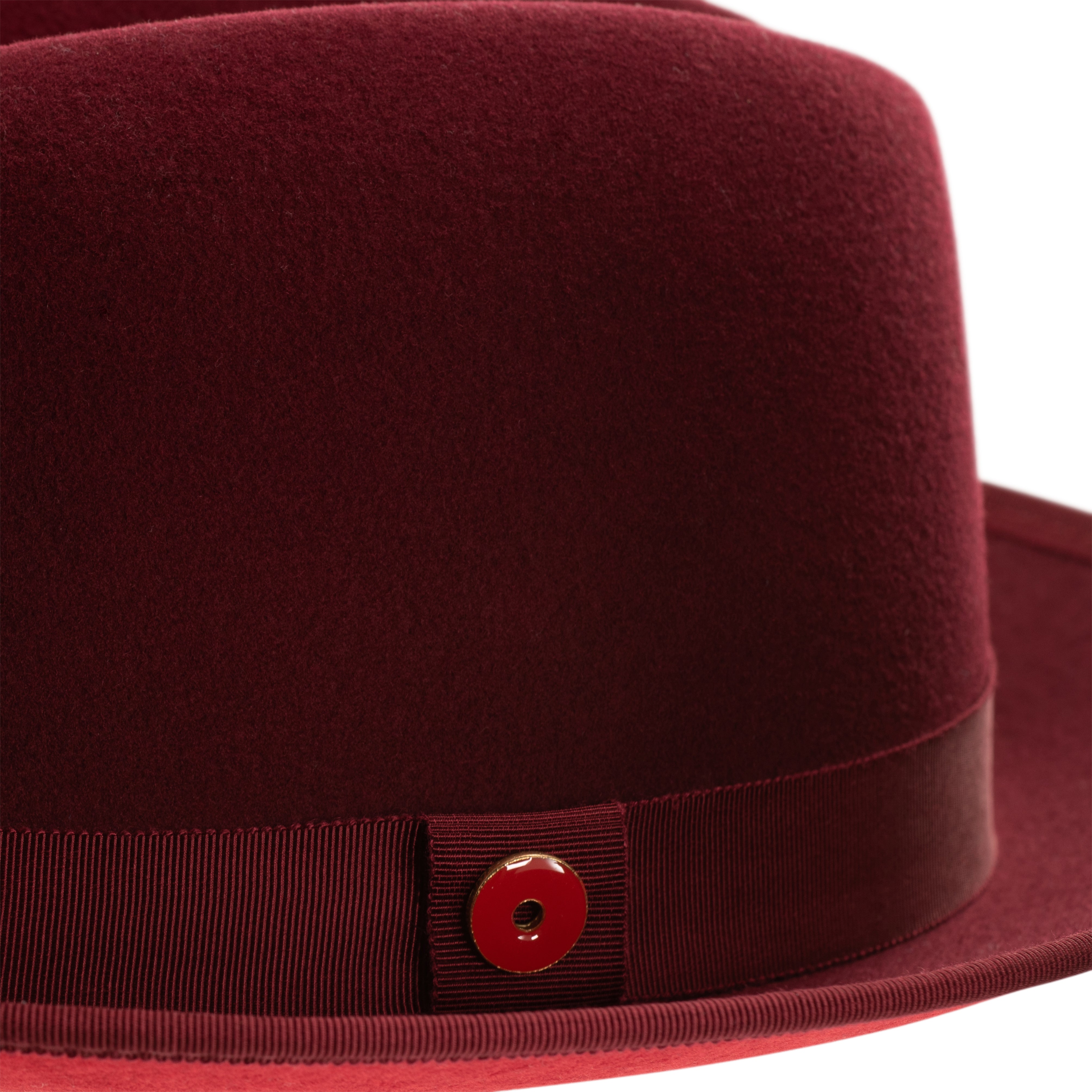 A classic center-creased fedora hat in old maroon color with a 2.5 inch curved brim, classic ribbon trim, a signature logo pin, and a red bottom brim.