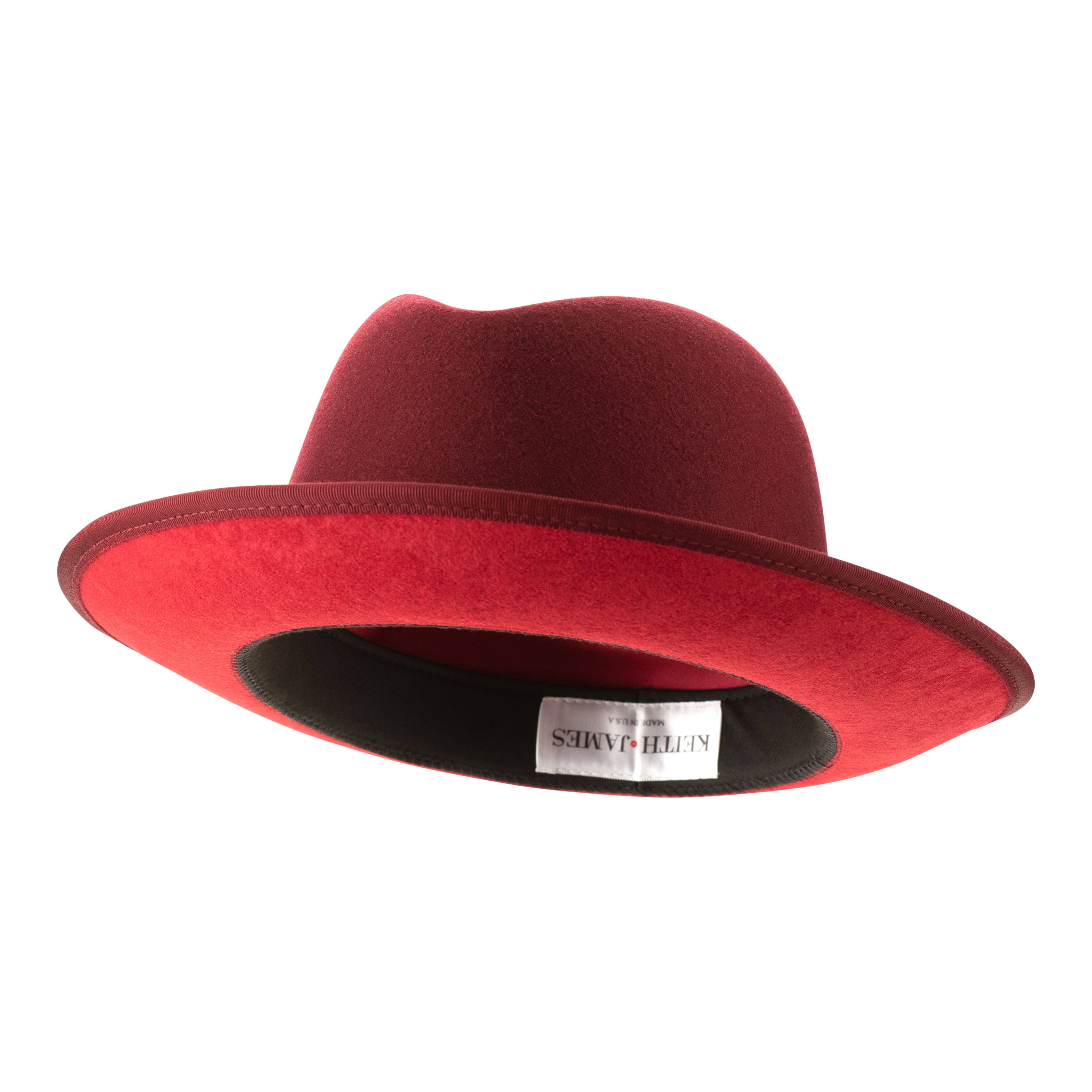 A classic center-creased fedora hat in old maroon color with a 2.5 inch curved brim, classic ribbon trim, a signature logo pin, and a red bottom brim.