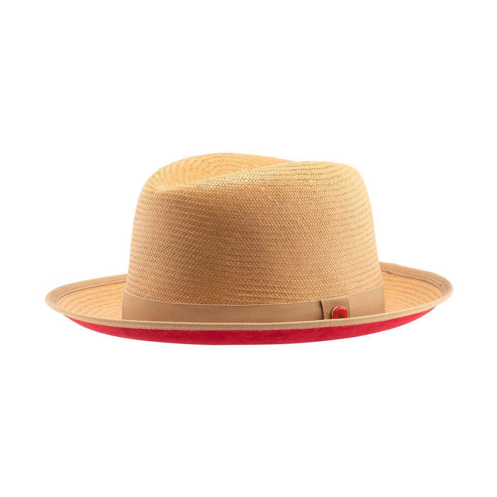 A golden honey straw fedora hat with a red bottom brim and a signature logo pin.