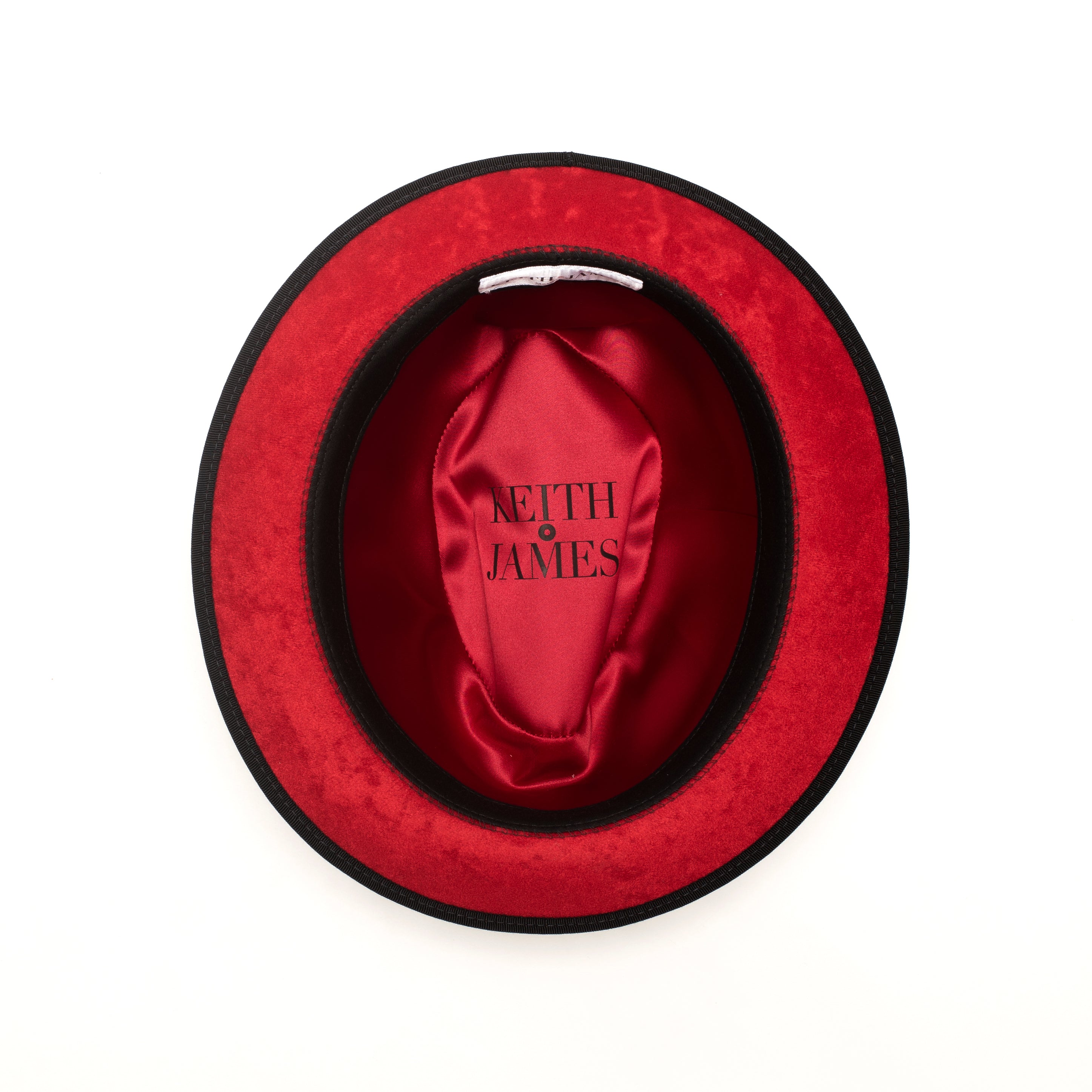 A black pinched crown fedora hat with a red bottom brim and a signature logo pin.