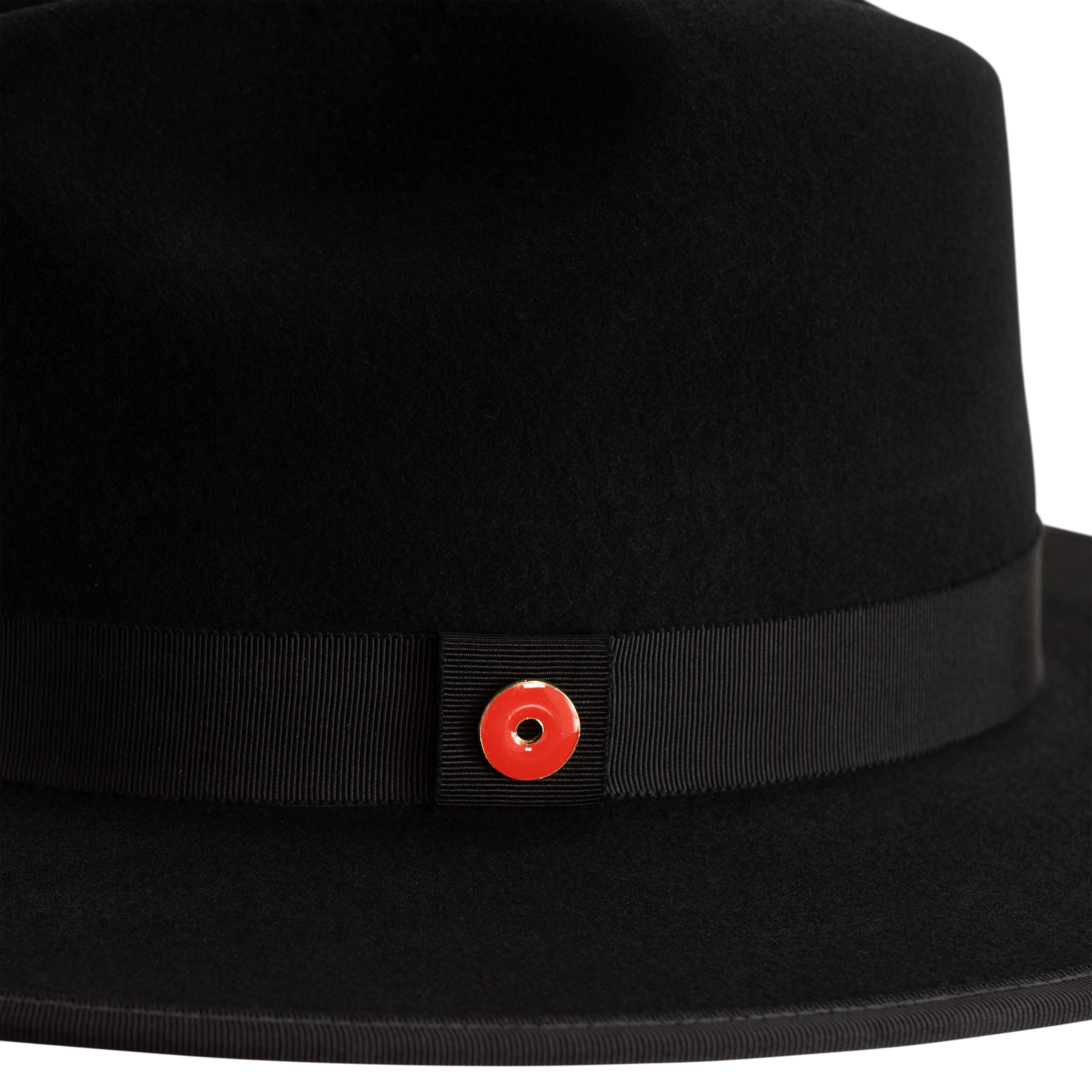 A jet black fedora hat with a pinched crown, flat brim, and bound edge. It includes a classic ribbon trim, a signature logo pin, and a red bottom brim.