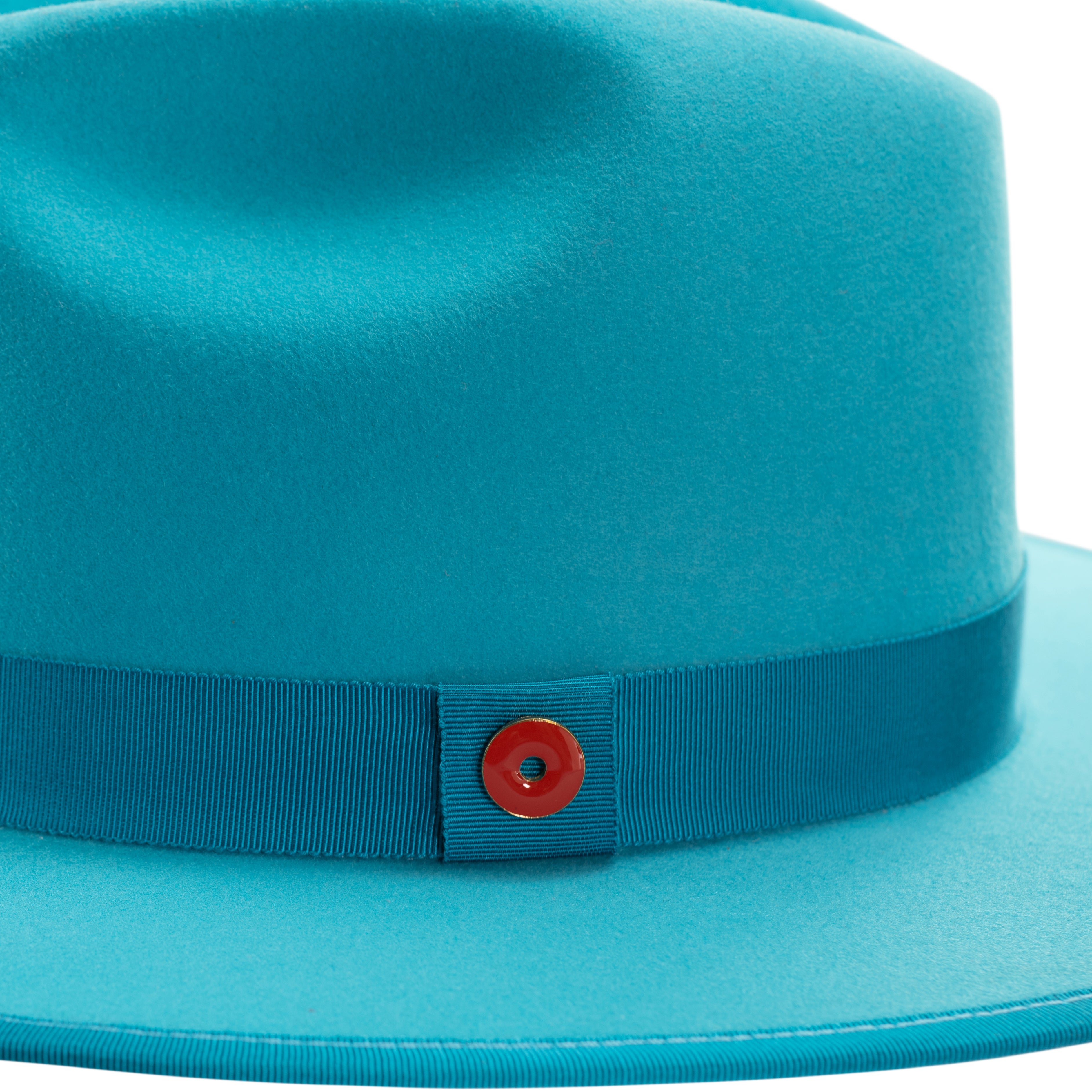 A blue fedora hat with a flat brim, pinched crown, and a classic ribbon trim including a signature logo pin on the side.