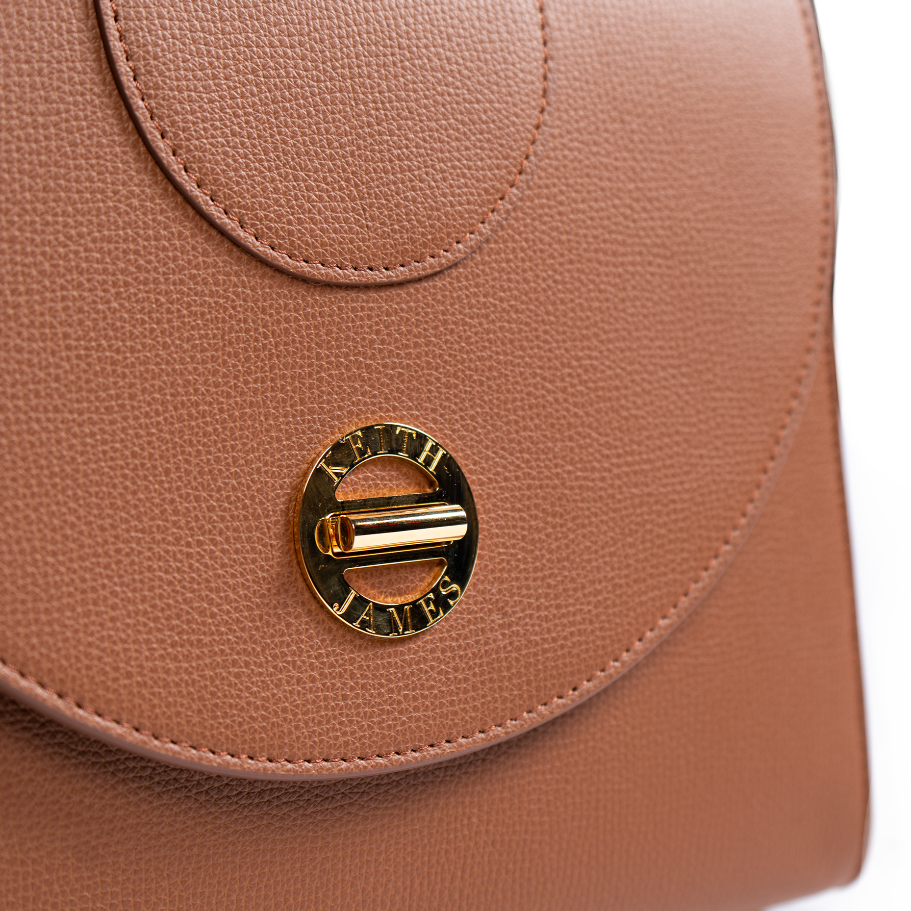 A cocoa brown top handle handbag with a microfiber lining, metallic hardware, and a flat pocket inside. The bag is crafted from leather.