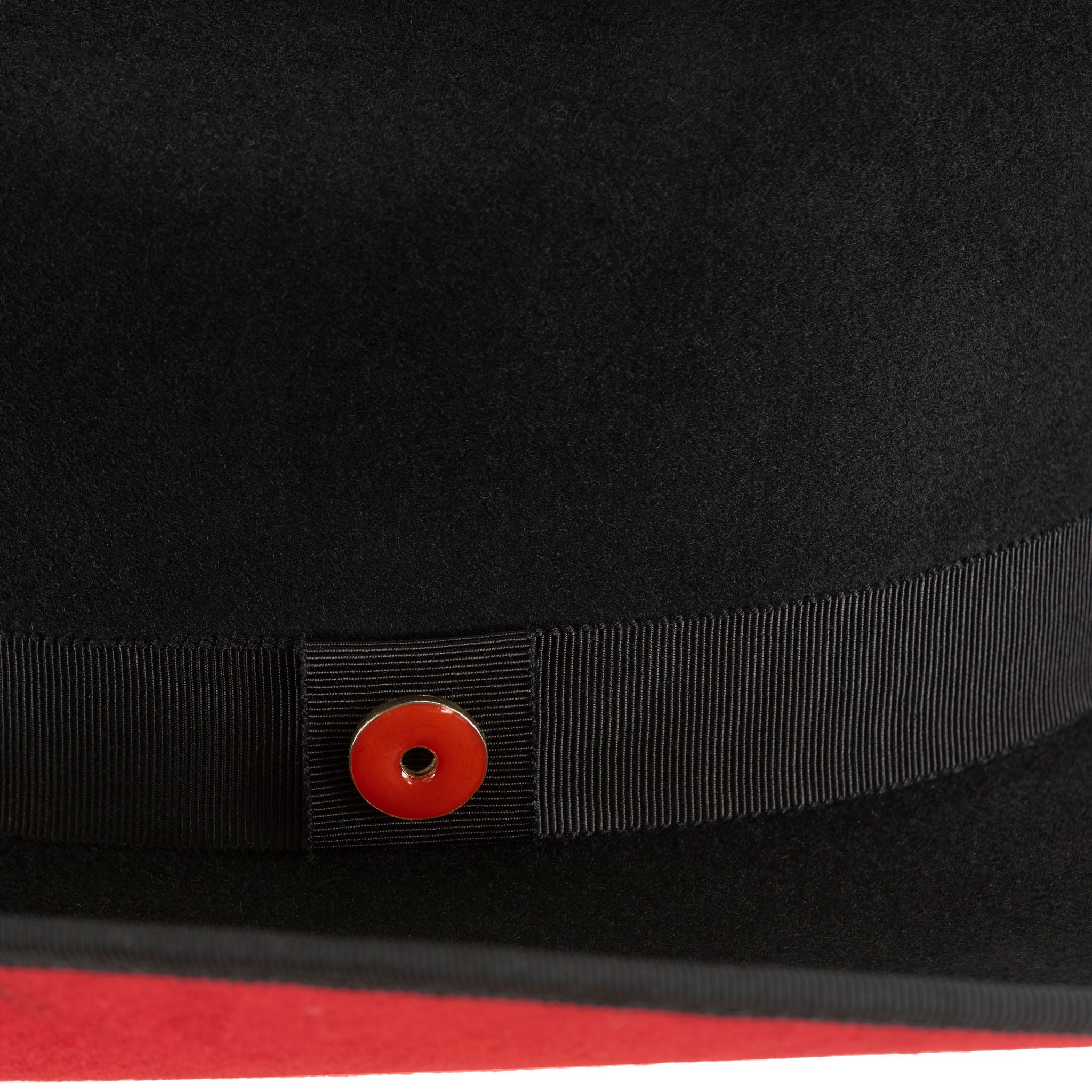 A black wool cowboy hat with a red sweatband, labeled with a brand logo pin.