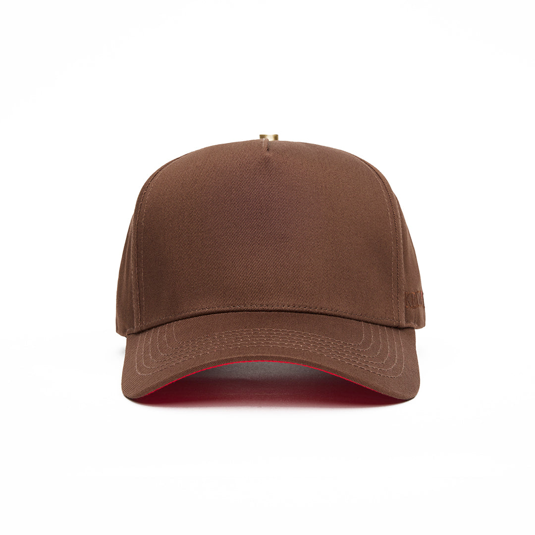 A cocoa brown 5 panel baseball cap with an adjustable band and a red bottom brim, featuring a logo embroidered on the front.
