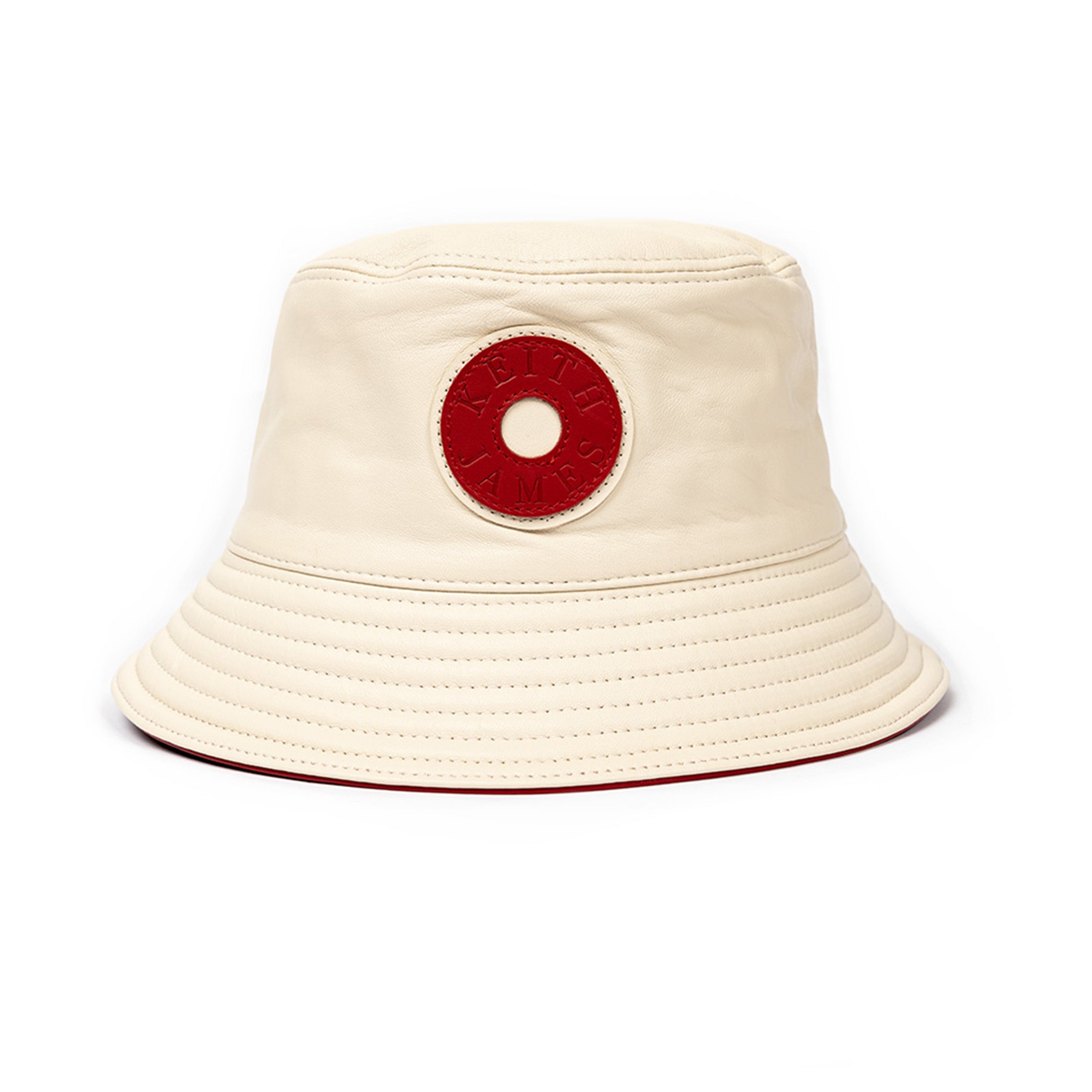 A beige leather bucket hat with a red stamped leather logo circle on the front.