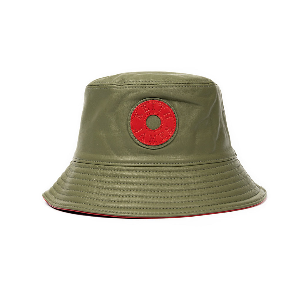 A olive green bucket hat made of leather with a red stamped leather logo circle on the front.