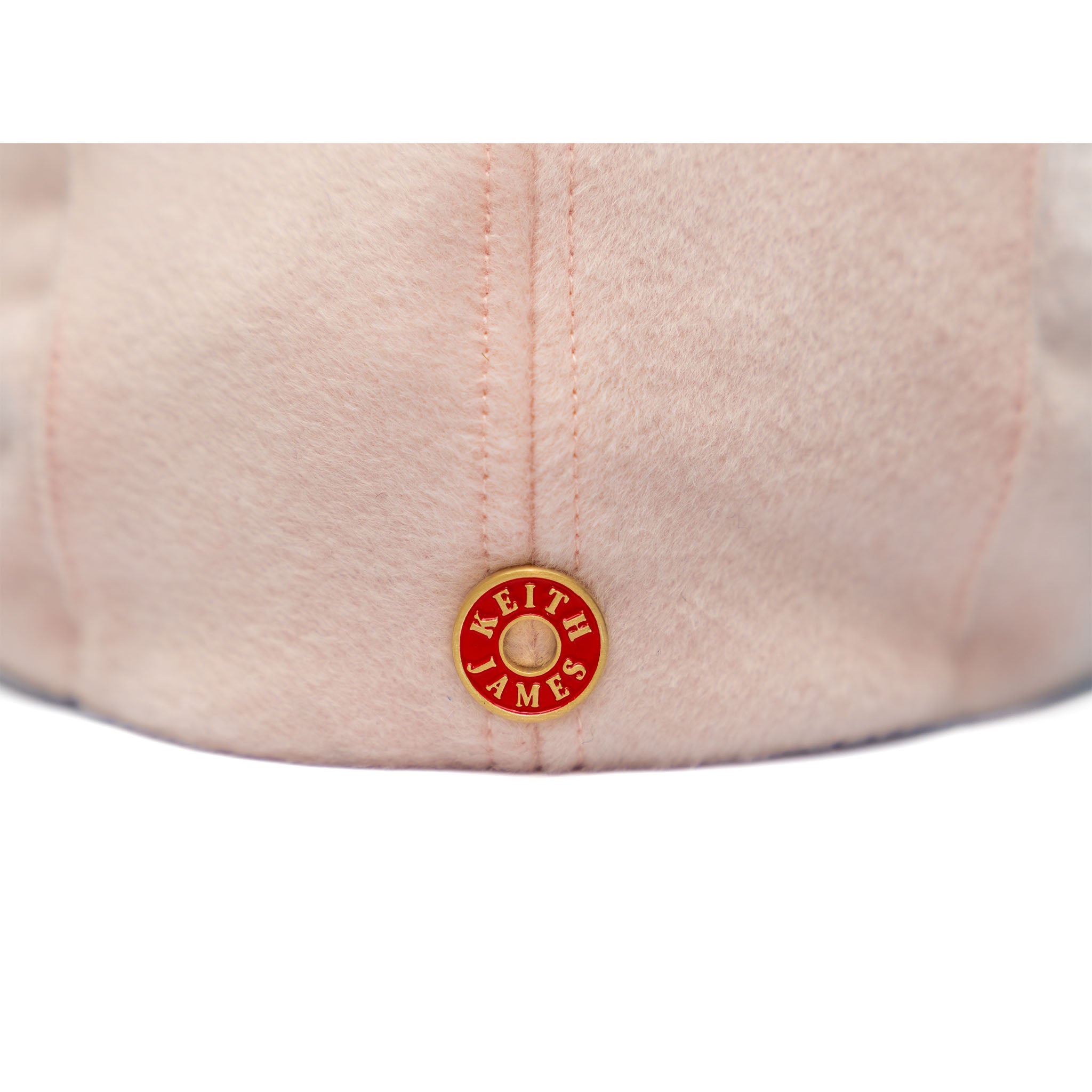 A soft pink newsboy cap with a flat visor, made of Australian wool, featuring a satin lining and gold hardware.