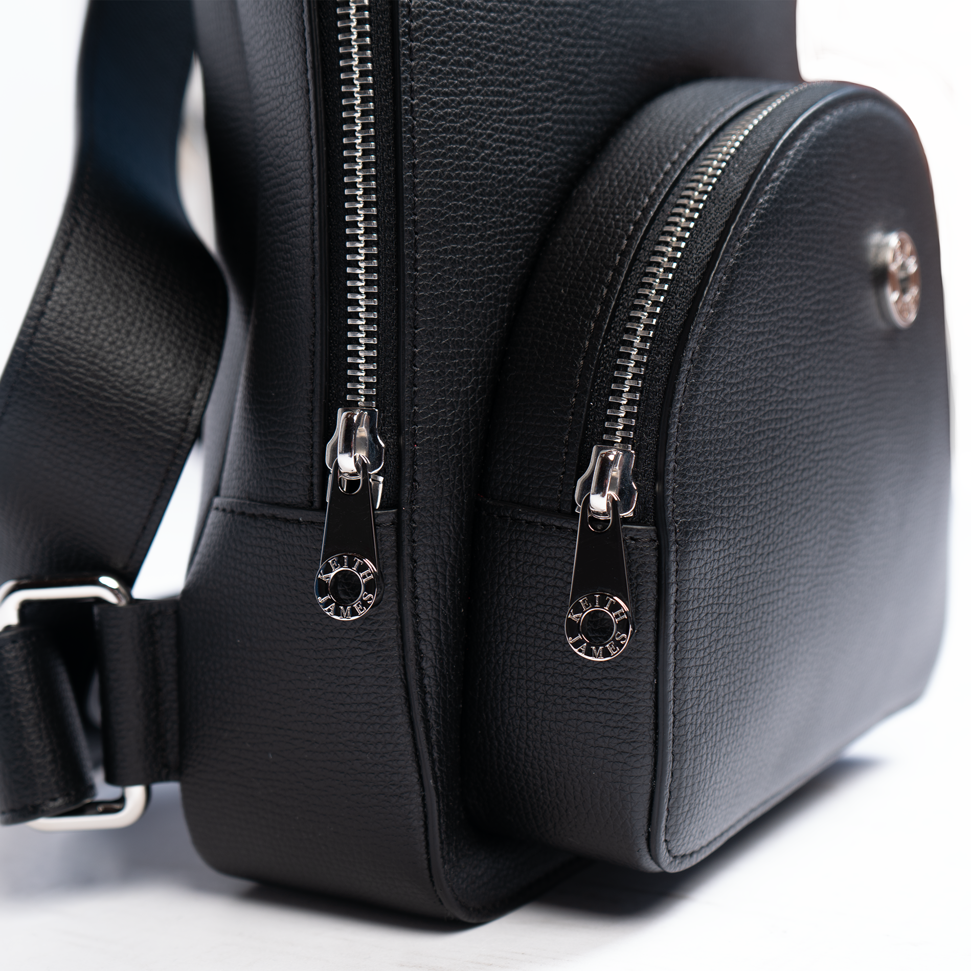 A jet black, leather backpack with a front pocket and a central zipper closure. The backpack features a compact design suitable for personal use.