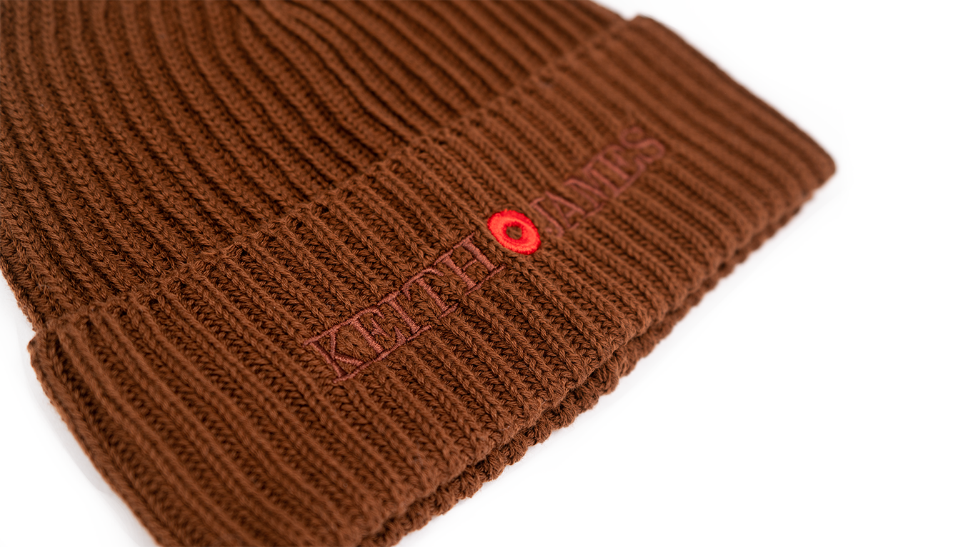 A cocoa brown rib-knit beanie with an embroidered logo on the front.