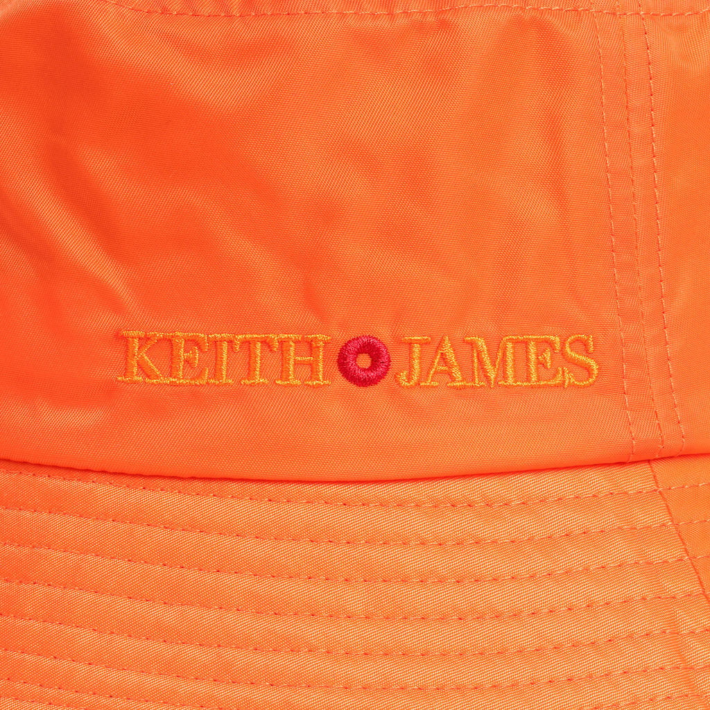 A citrus orange bucket hat with the text 'KEITH JAMES' embroidered on the front.