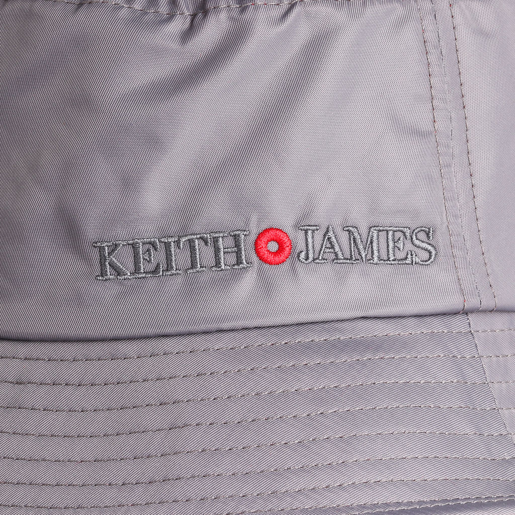 A cool grey bucket hat with a red band around the base, featuring a logo on the front.