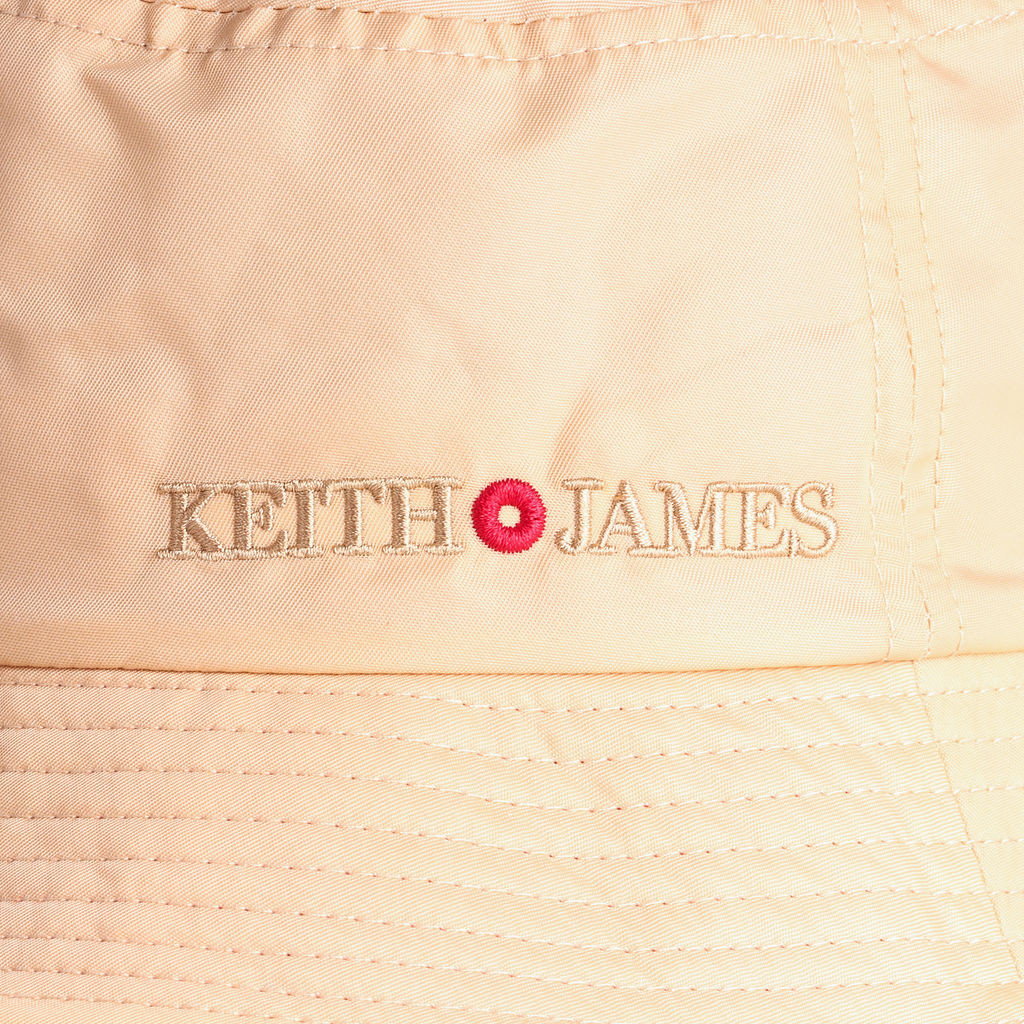 A beige bucket hat with the brand name 'KEITH JAMES' embroidered on the front.