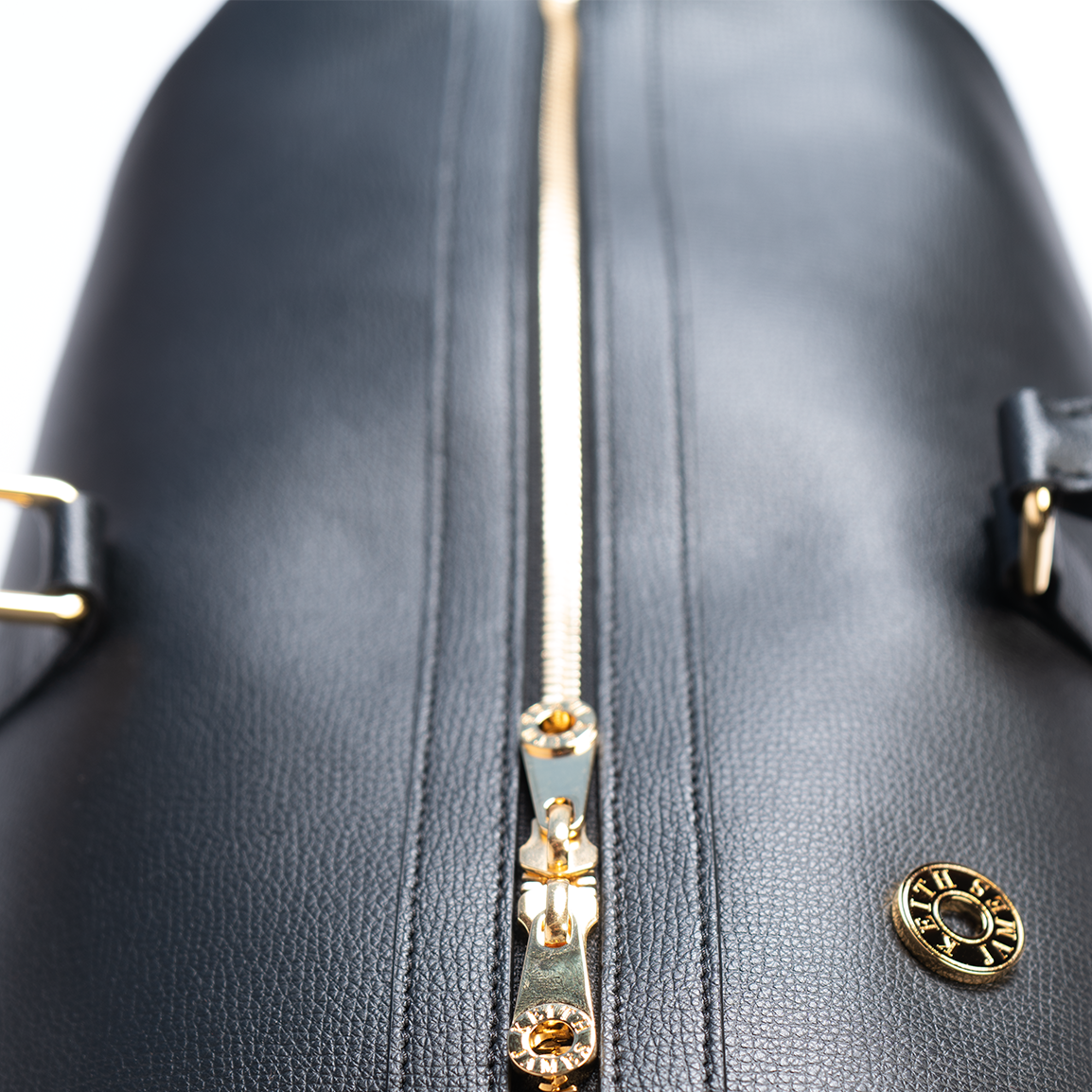 A jet black duffel bag with a detachable strap and gold-tone hardware on a white background.