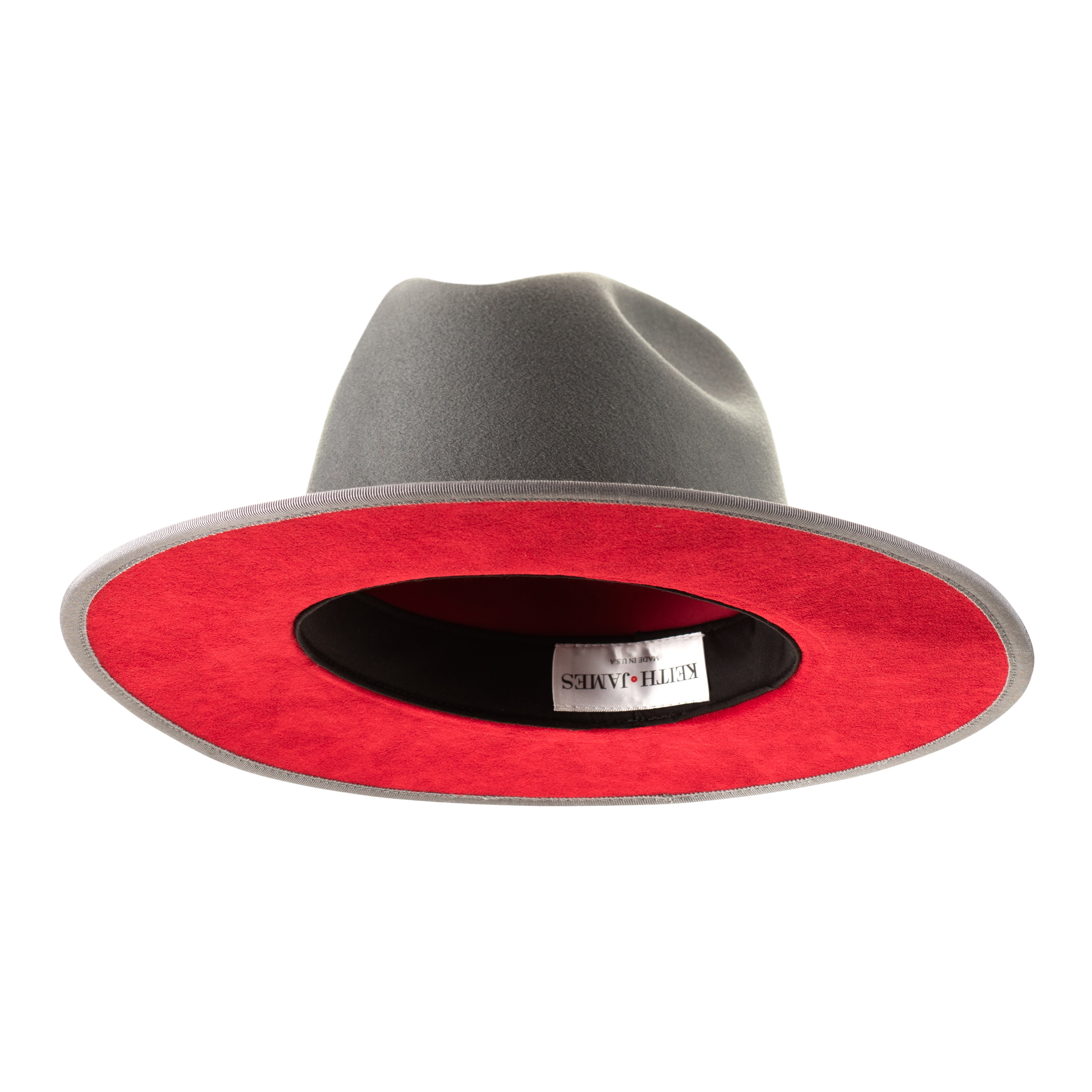 A cool grey pinched crown fedora hat with a flat brim and a classic ribbon trim, including a signature logo pin and red bottom brim.