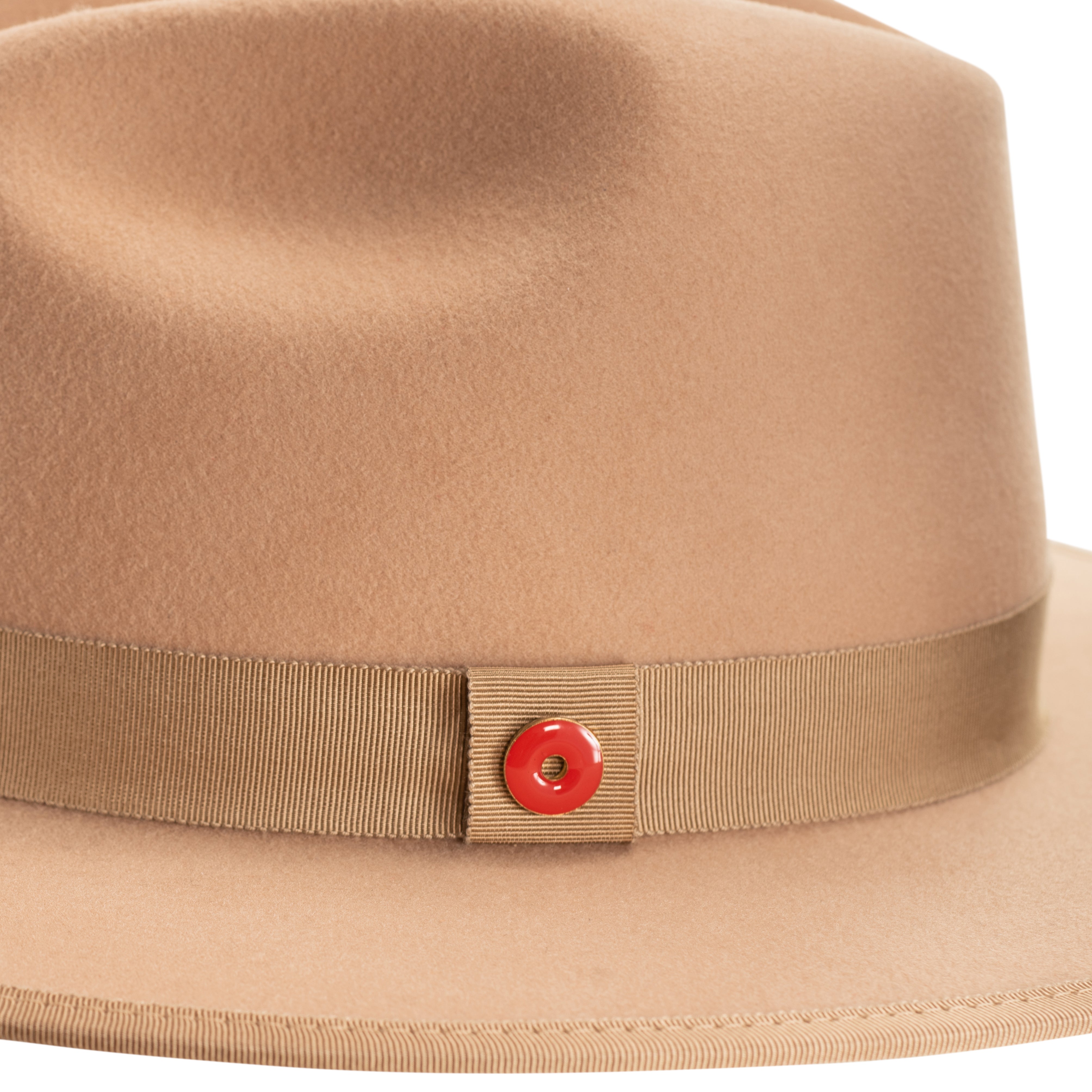 A golden honey fedora hat with a pinched crown, flat brim, and bound edge. It includes a classic ribbon trim, a signature logo pin, and a red bottom brim.