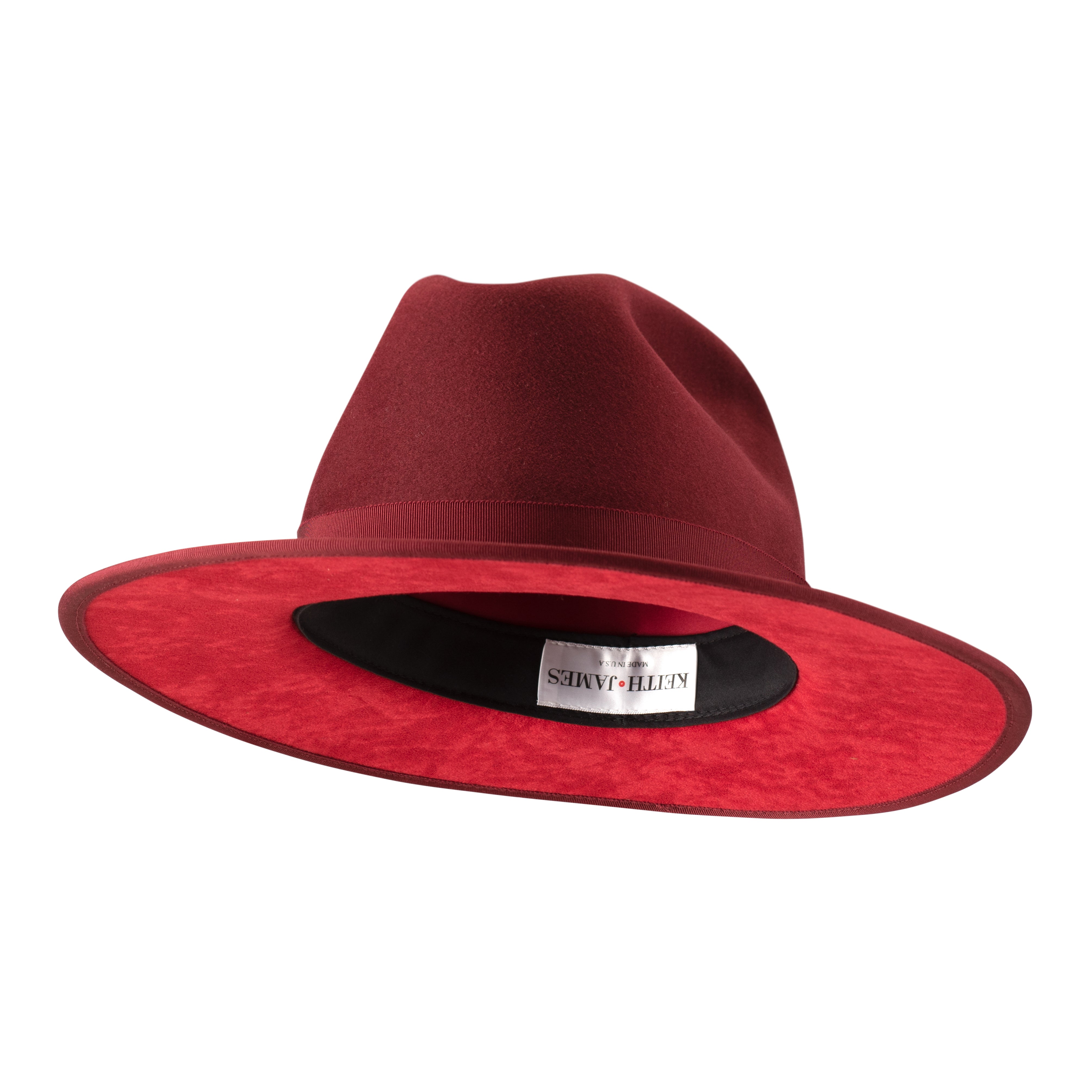 A maroon colored fedora hat with a flat brim and a classic ribbon trim, featuring a signature logo pin on the side.