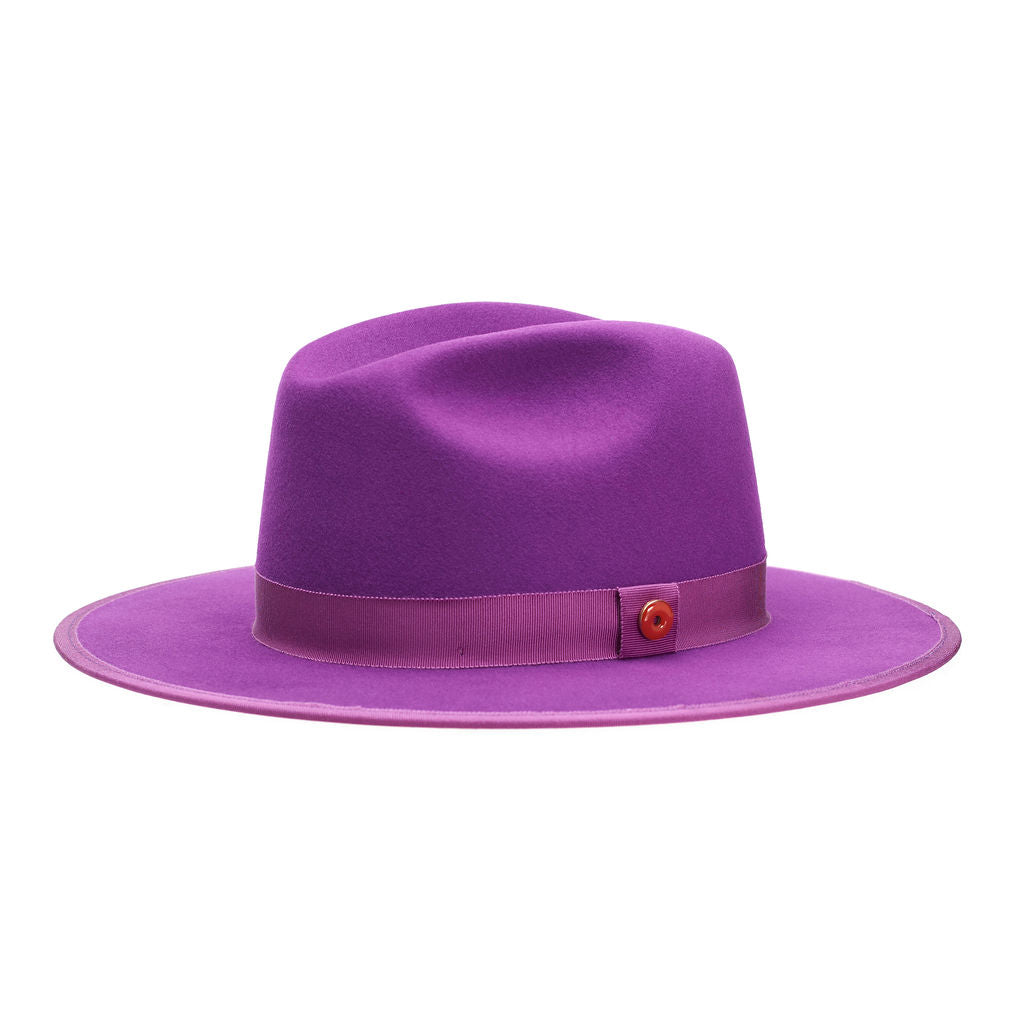 A violet purple fedora hat with a flat brim and a classic ribbon trim, featuring a signature logo pin and a red bottom brim.