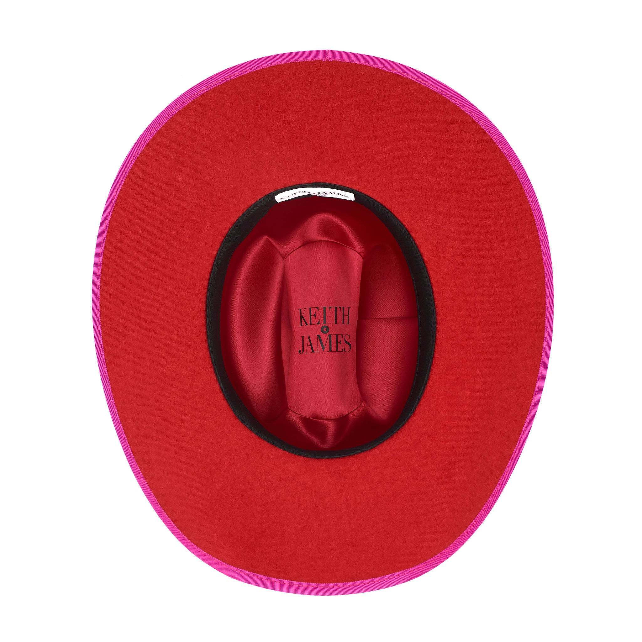 A hot pink cowboy hat with a red suede brim and a logo pin.